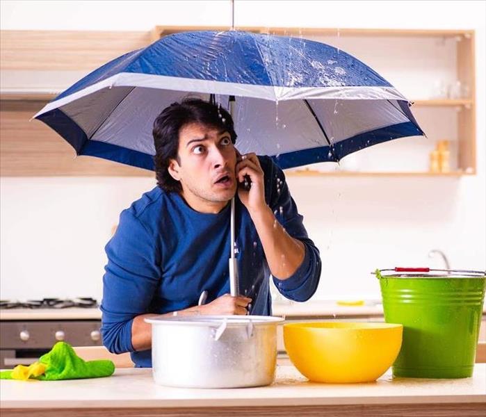 Man in home with umbrella over head