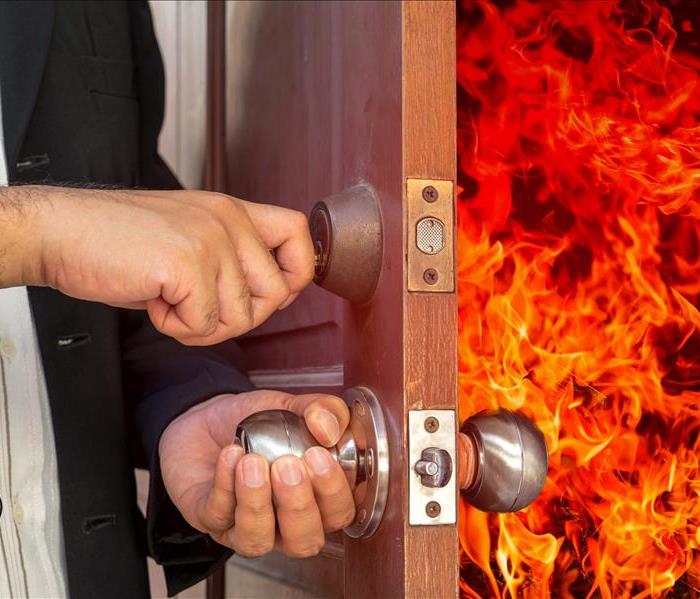 Man opening door with fire behind it as it as opened.